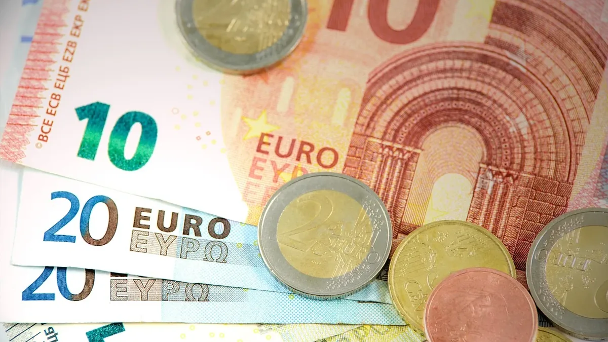 A collection of Euro banknotes and coins, with the banknotes featuring denominations of 5, 10, and 20 Euros.